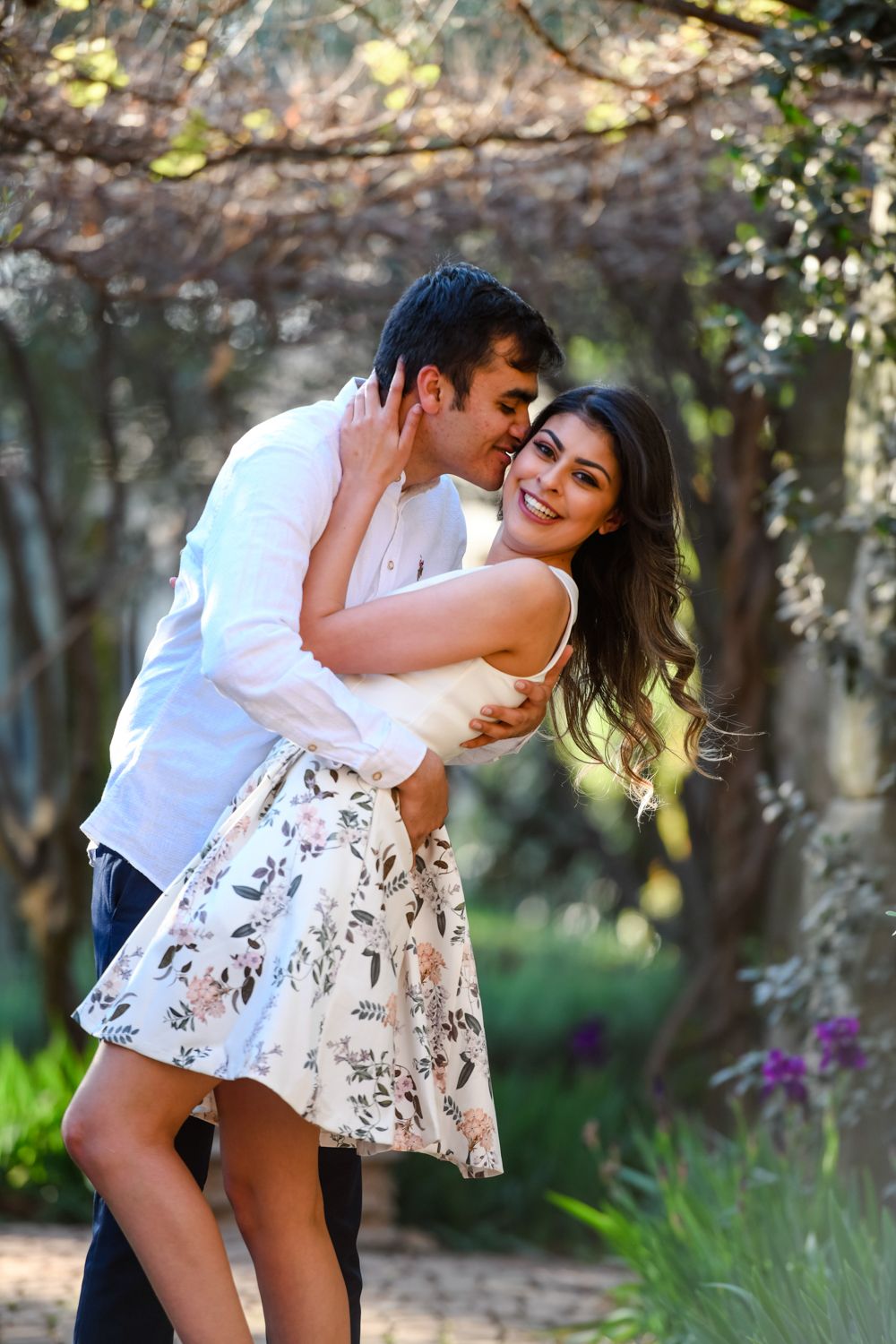 Couple laughing and embracing under an archway during their engagement shoot.