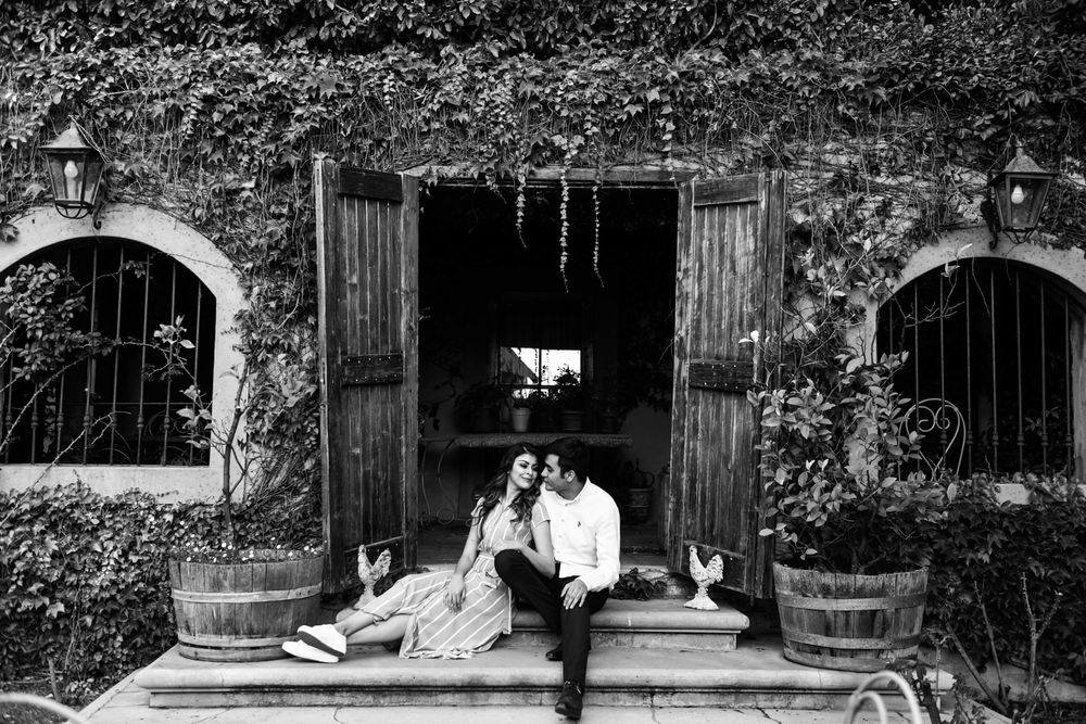 Black and white wide shot of a couple posing on the steps of a historic-style venue.