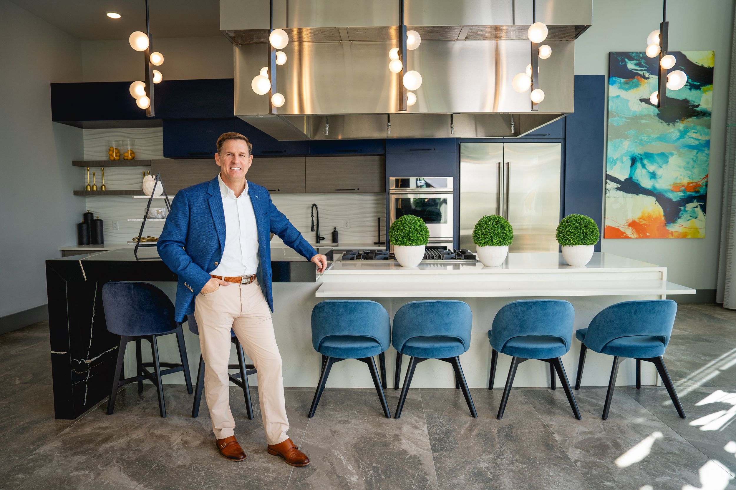 Modern luxury kitchen interior with blue velvet bar stools, pendant lighting, and marble countertops in contemporary home.
