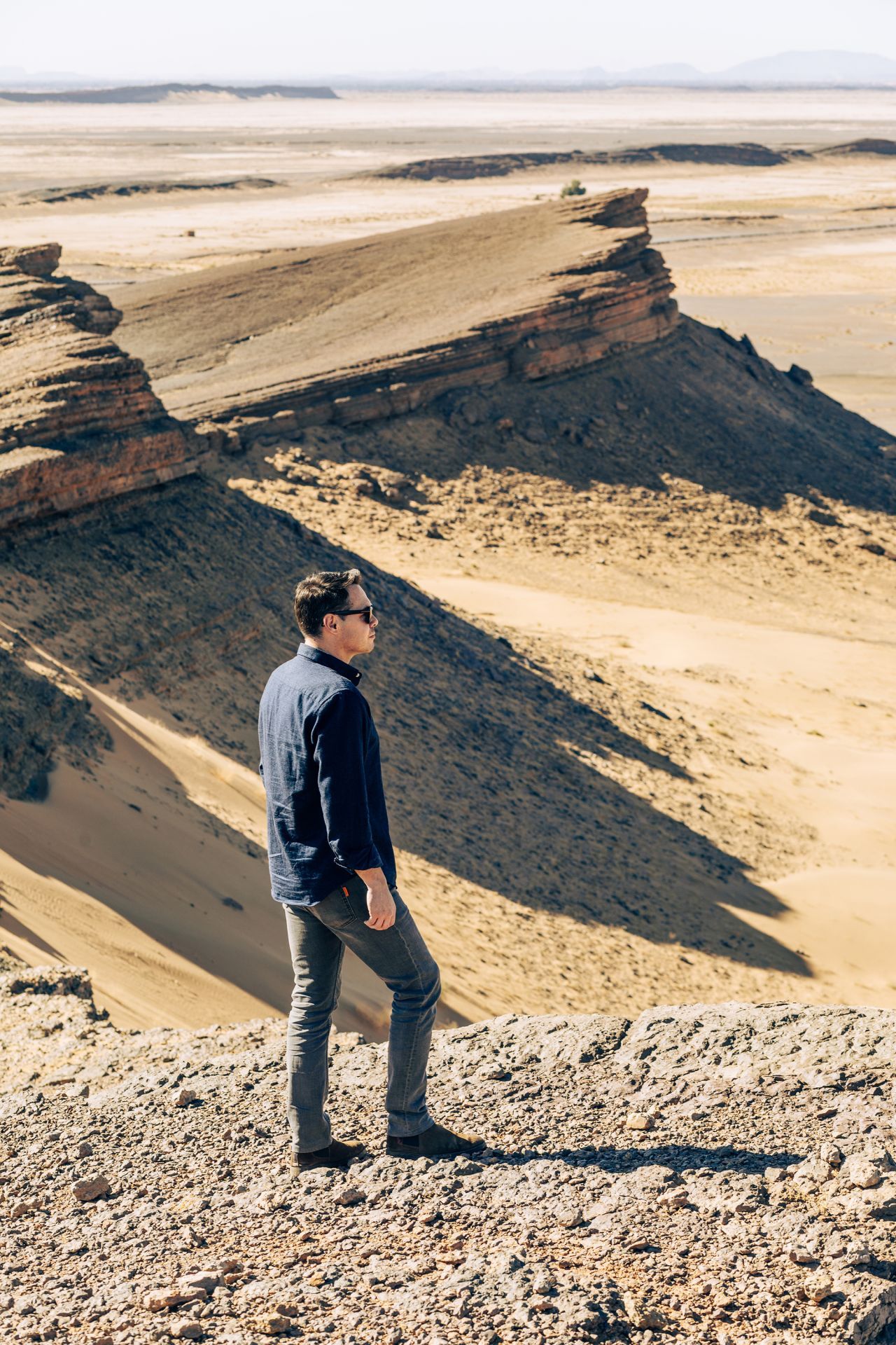 A selfie taken in a desert landscape at sunset with dramatic sunlight creating a lens flare effect.