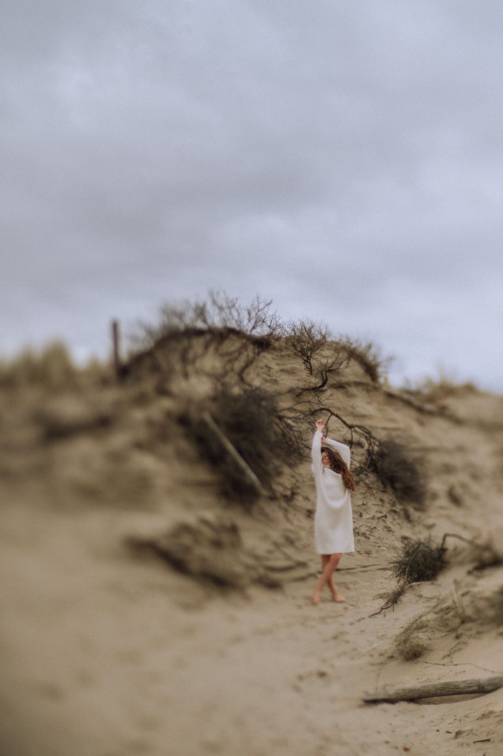 Misty sand dunes create a dramatic landscape under an overcast sky.