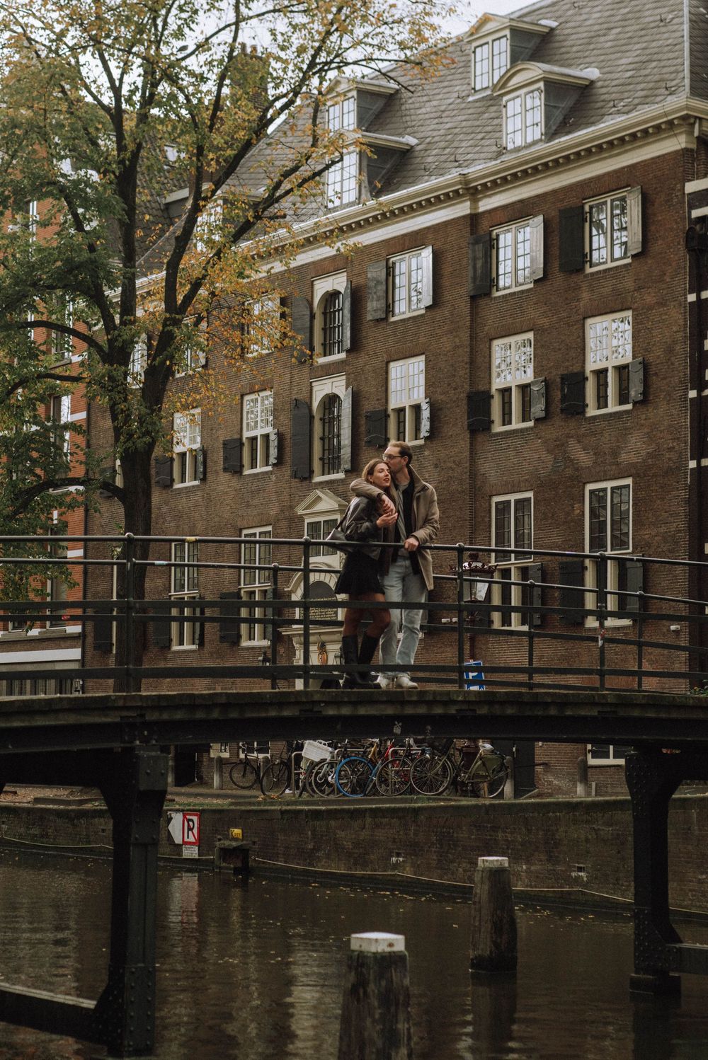 Romantic scene on a historic bridge over canal with brick buildings in background.
