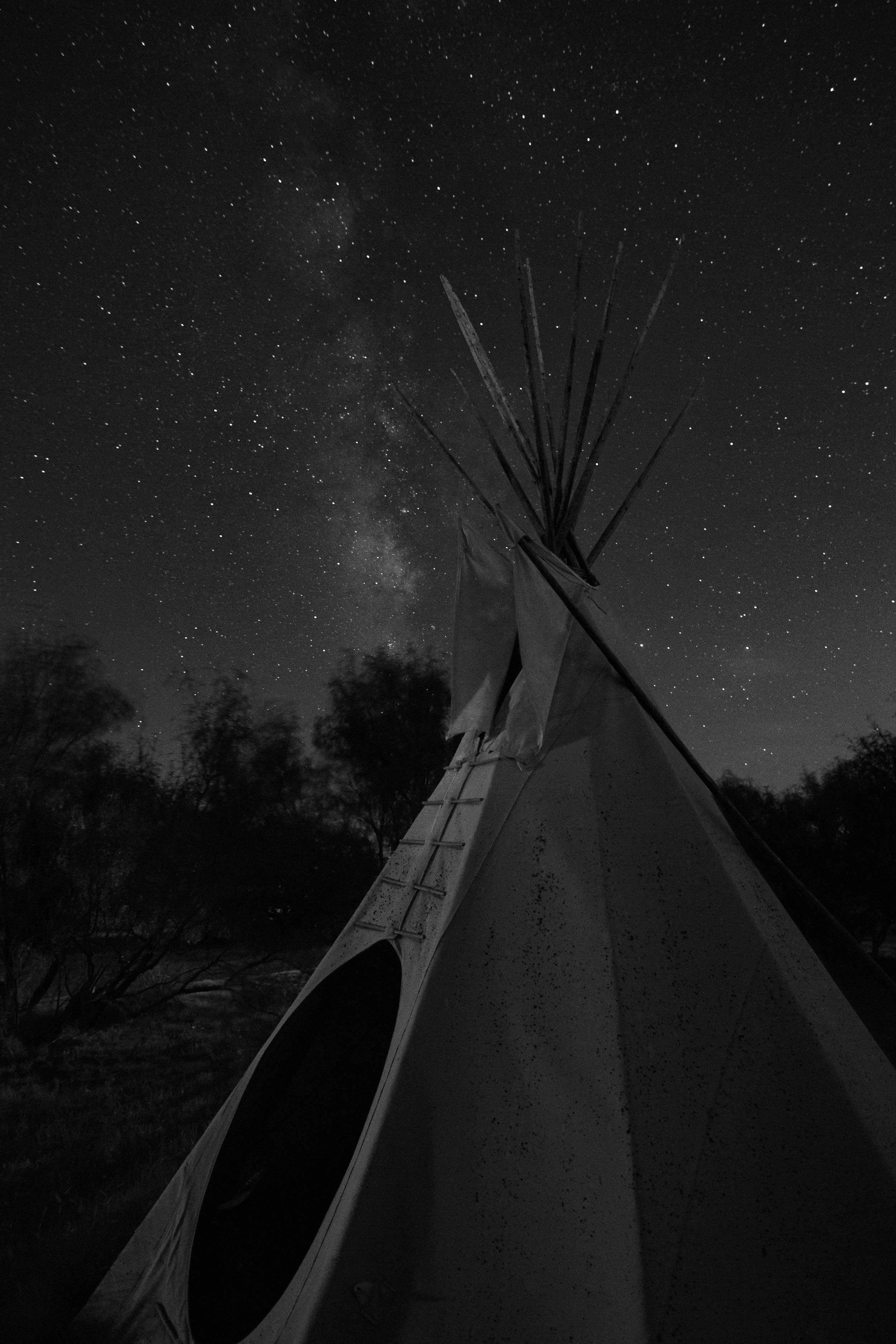 Traditional Native American teepee silhouetted against starry night sky with visible Milky Way at the Hideout at Palo Duro Canyon State Park