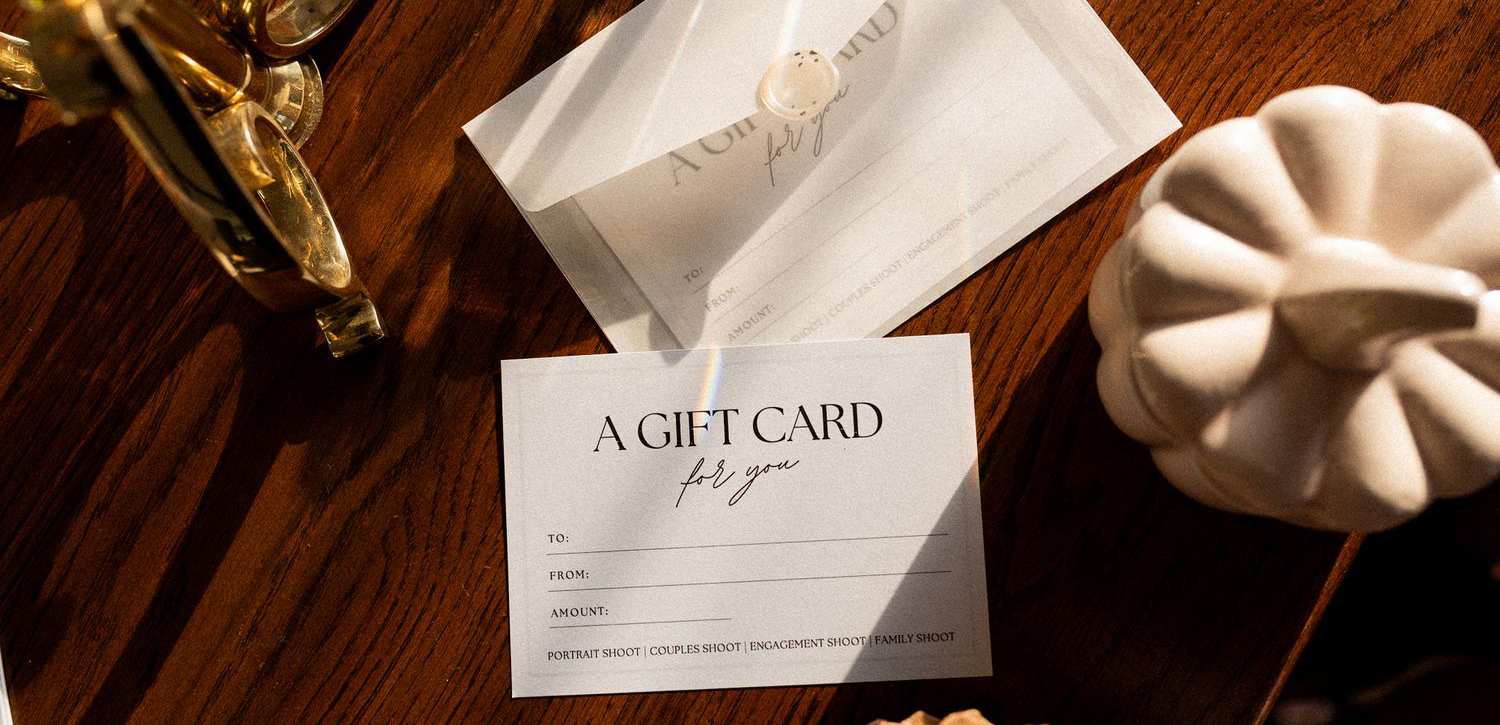 A stack of elegant white gift cards displayed on a wooden surface with elements around them.