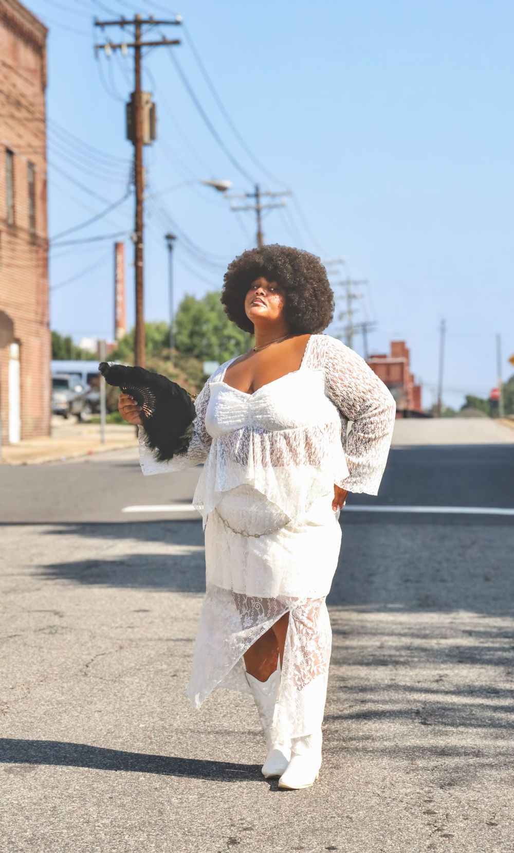 A white lace dress photographed against an urban backdrop with power lines and brick buildings.