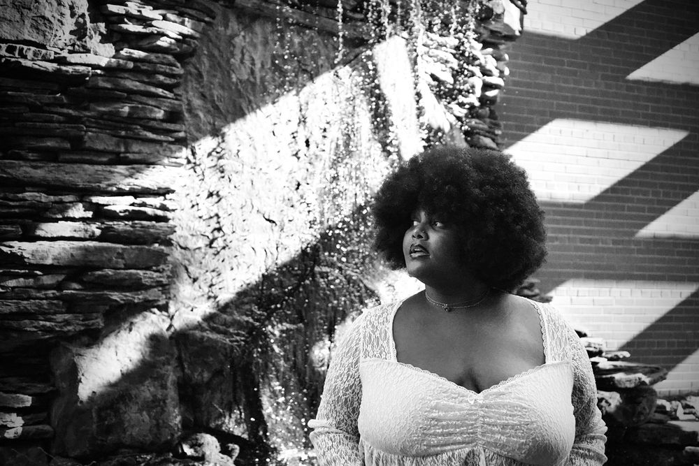 Black and white portrait showcasing dramatic lighting against a textured stone wall background.