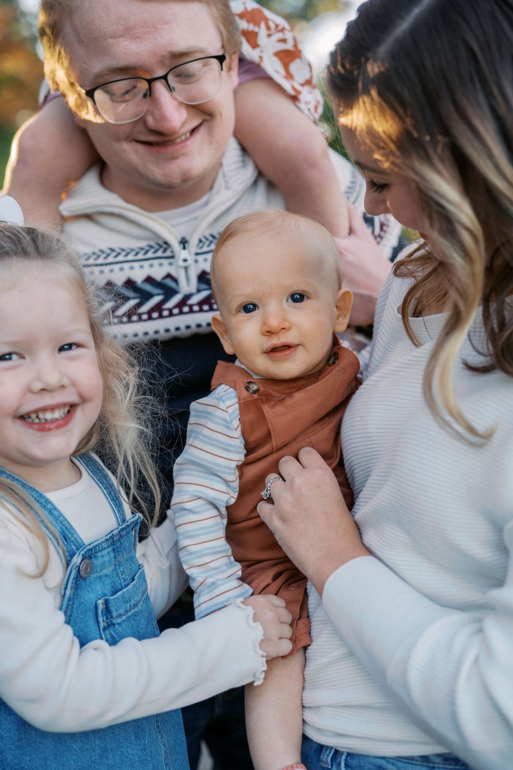 Candid family portraits showing joyful moments in white sweaters and denim against a natural backdrop.