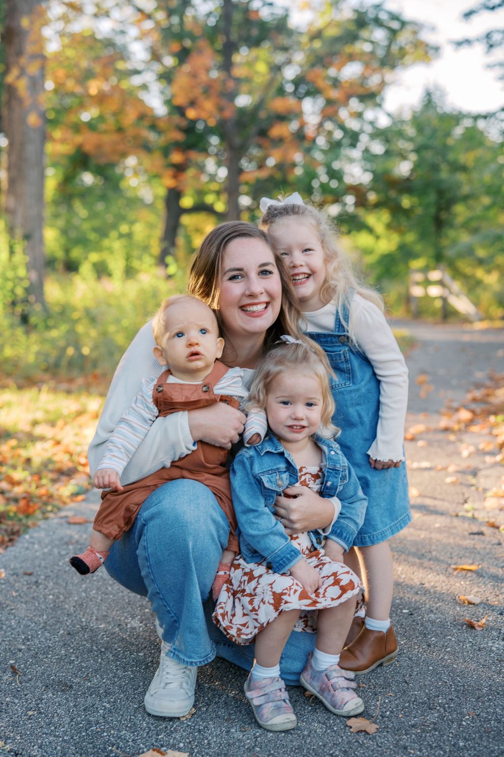 Casual outdoor family photo session on a path with autumn trees in the background.