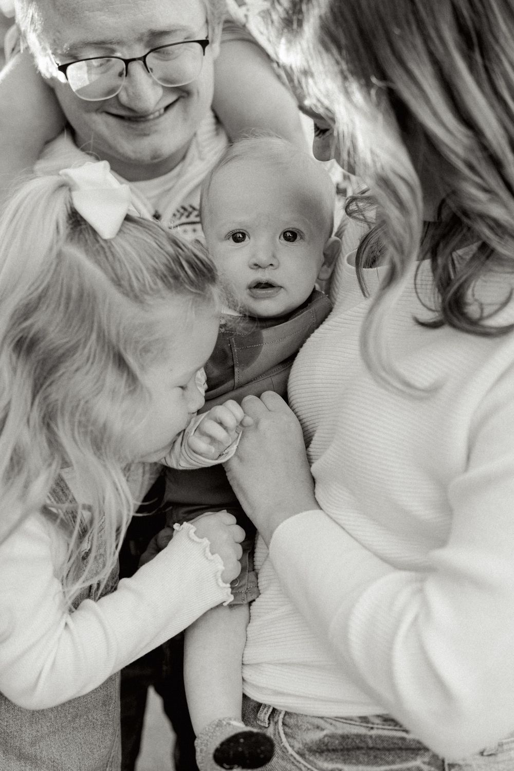 A series of close-up black and white candid family moments showing warmth and affection.