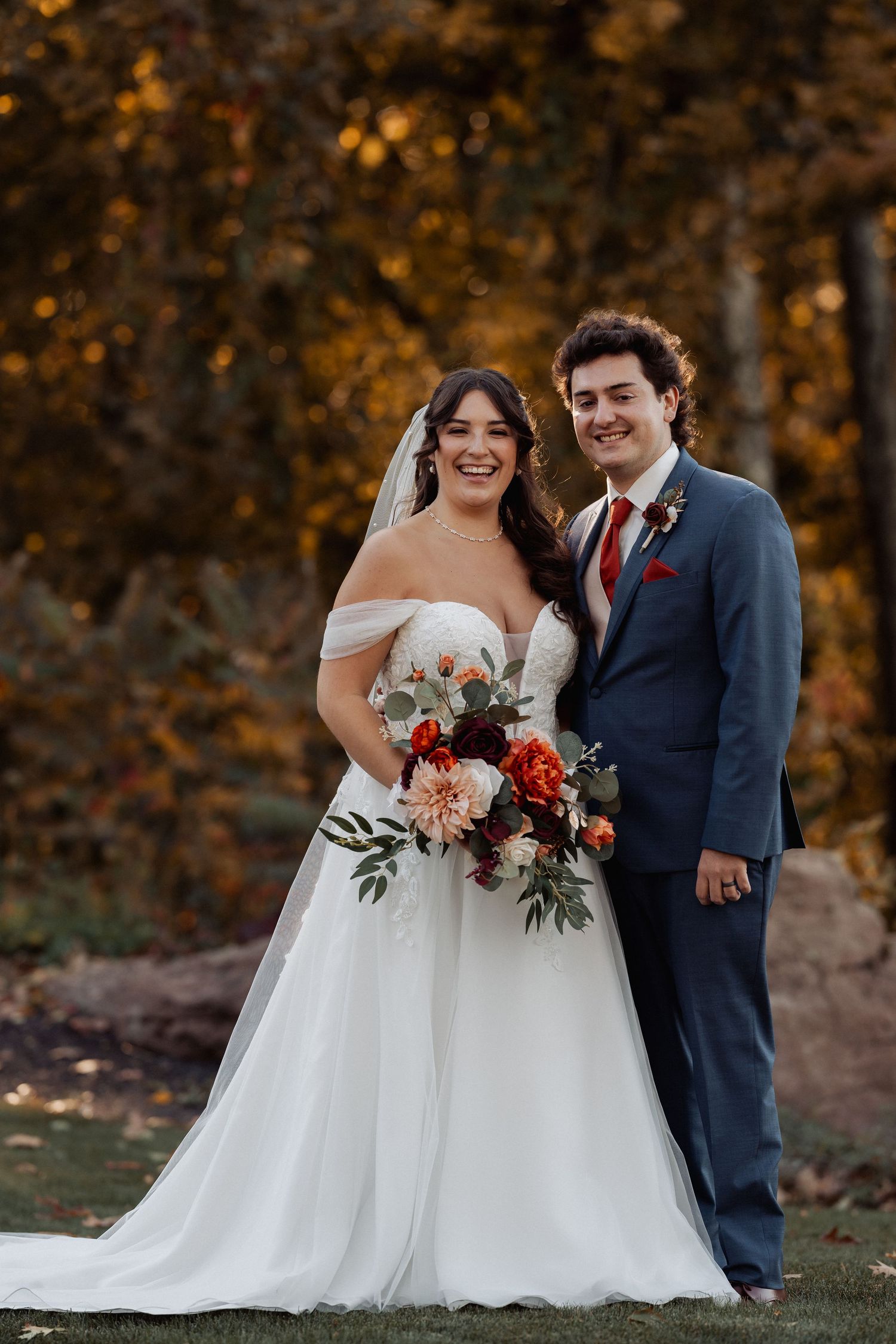 A white wedding dress with delicate lace appliques and a sweetheart neckline hangs elegantly on a black hanger against a dark wall.