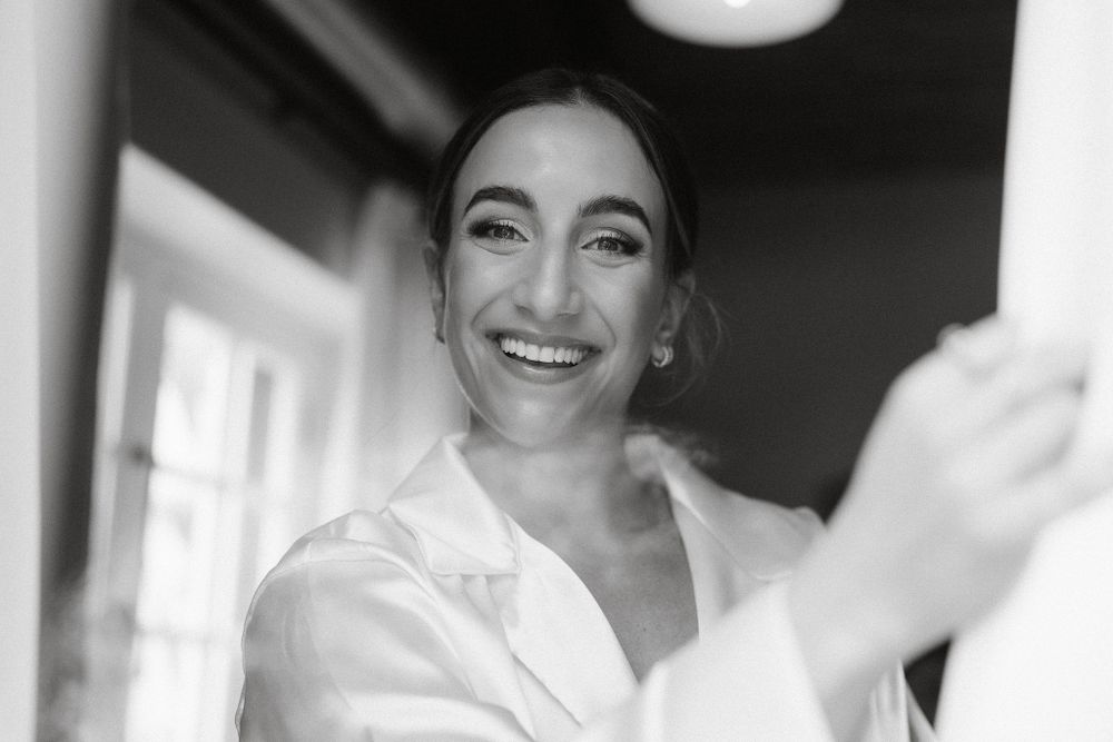 A joyful moment captured in black and white as someone gets ready on their wedding morning.