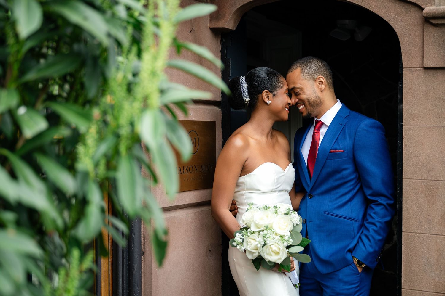 A couple shares an intimate moment in their wedding attire on a scenic lawn at sunset.