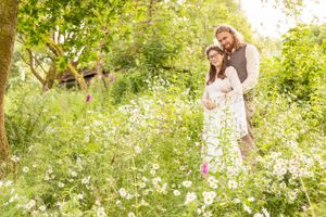 A newly married couple stand snuggled together among wild flowers in Gwynedd, North Wales, UK. Handfasting Photographer.