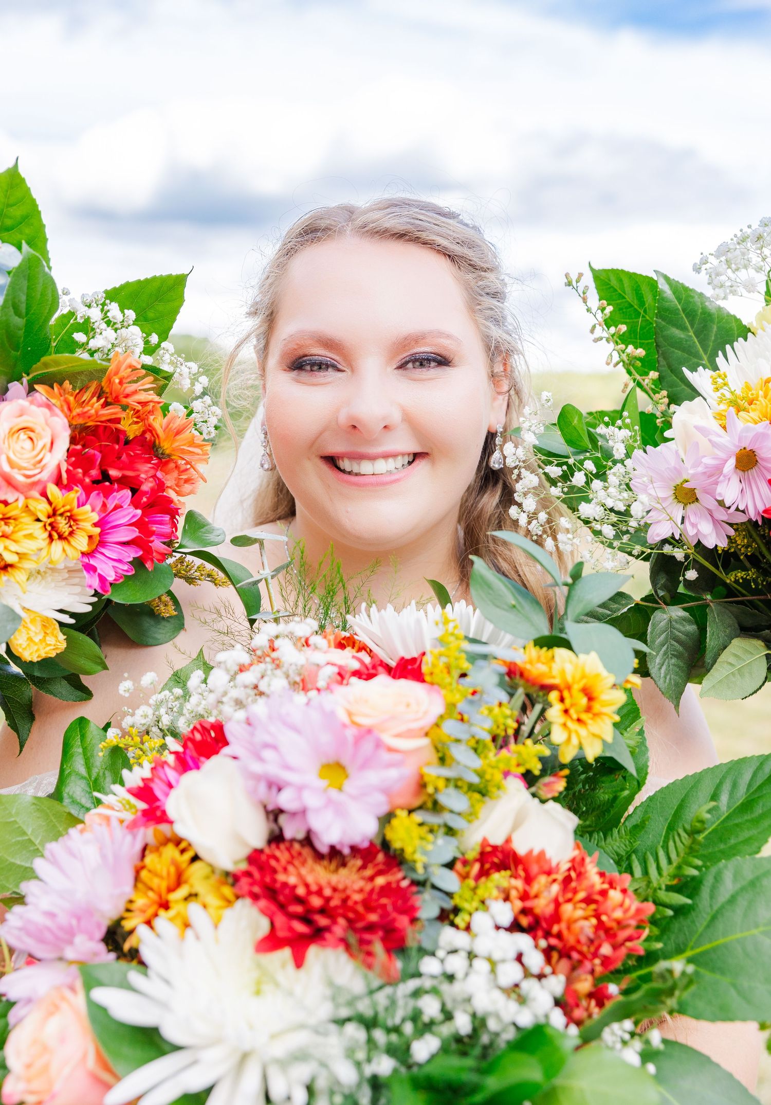 A vibrant wedding bouquet with colorful dahlias, roses and greenery frames the composition.