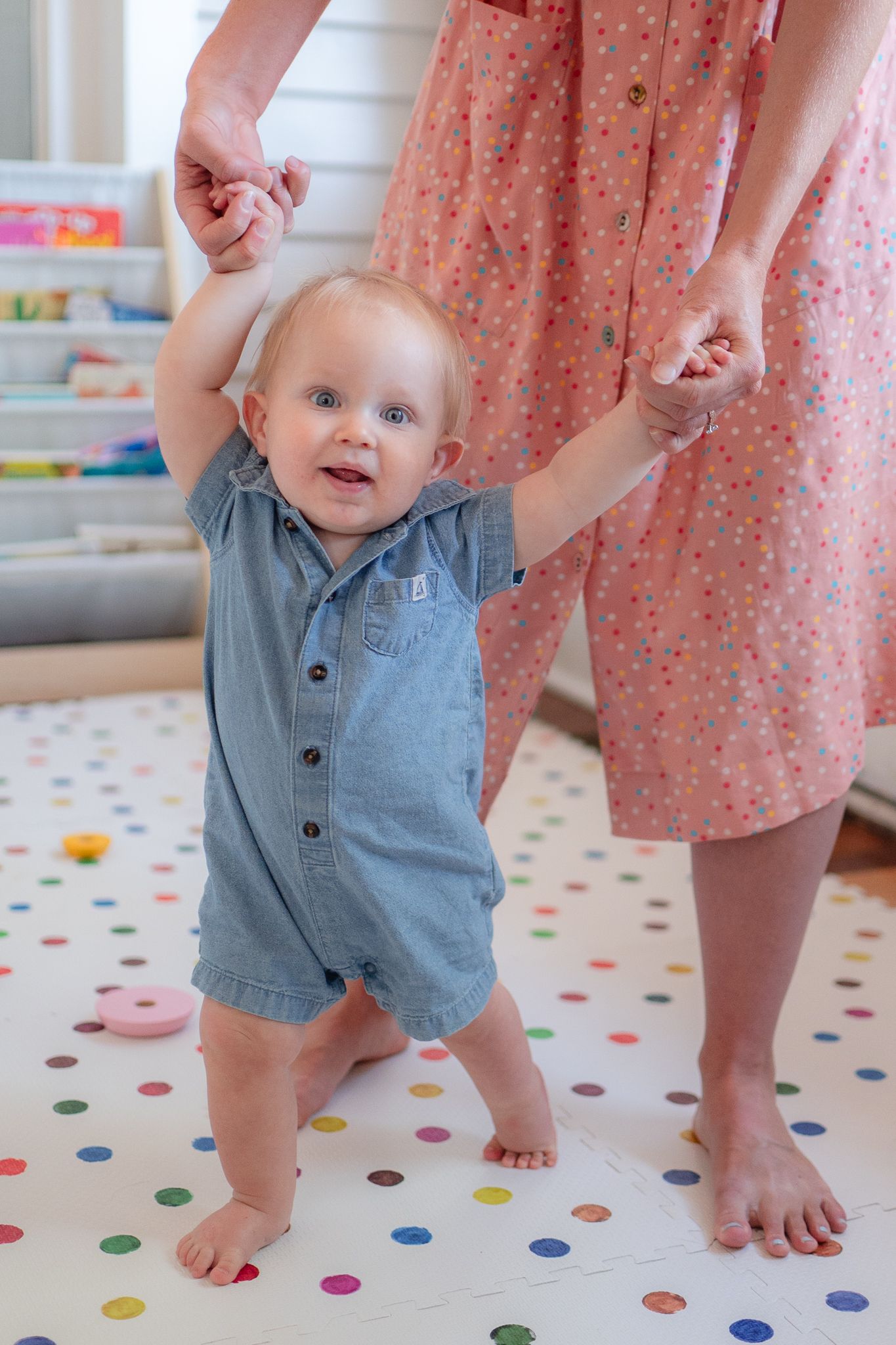 This one-year-old practices his walking skills, holding tight to mom's fingers.