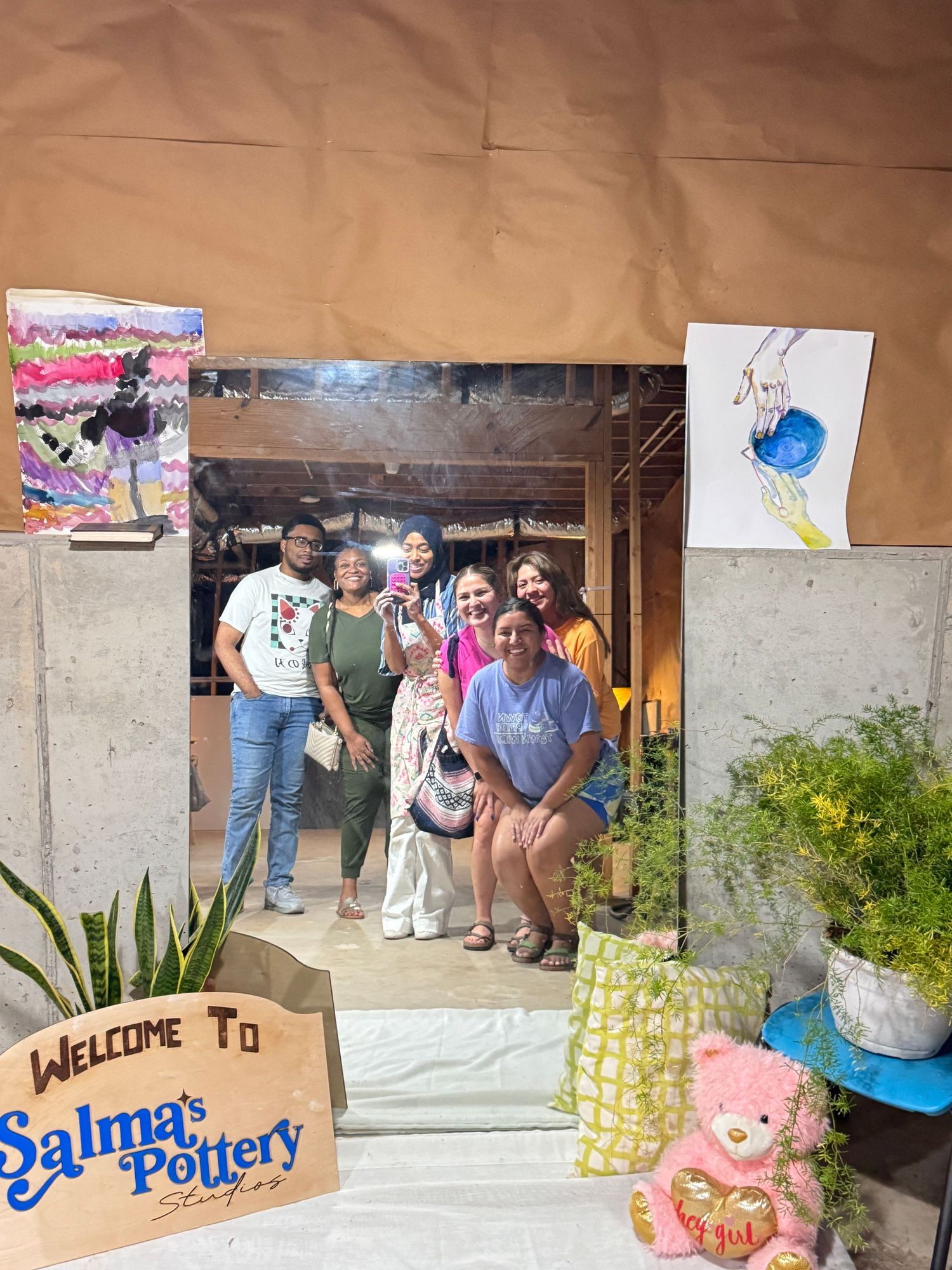 Group of friends posing at the entrance of Salma's Pottery Studio surrounded by artwork.