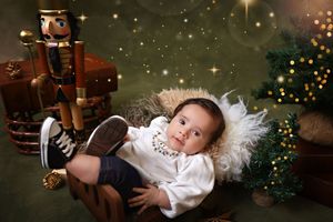 A magical Christmas photo series shows a child in white pajamas falling asleep while waiting for Santa Claus.