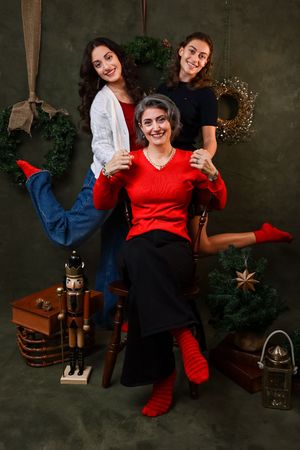 A series of holiday portraits showing two people in red and black outfits posing with festive decorations and greenery.