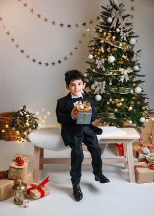 A festive holiday scene with a decorated Christmas tree, wrapped presents, and a figure seated on a white bench.