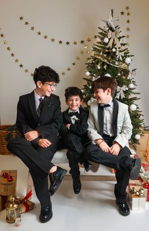 A sequence of five candid holiday photos showing people sitting and laughing together in front of a decorated Christmas tree.