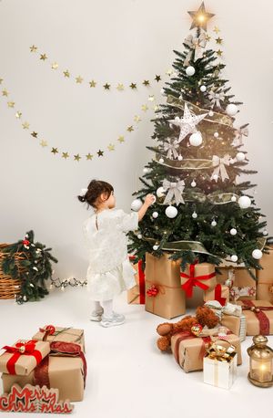 Festive Christmas scene with wrapped brown paper gifts, decorated evergreen tree, and gold star garland against white background.
