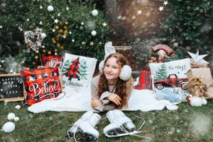 Holiday scene with ice skates and person lying on blanket surrounded by Christmas decorations.