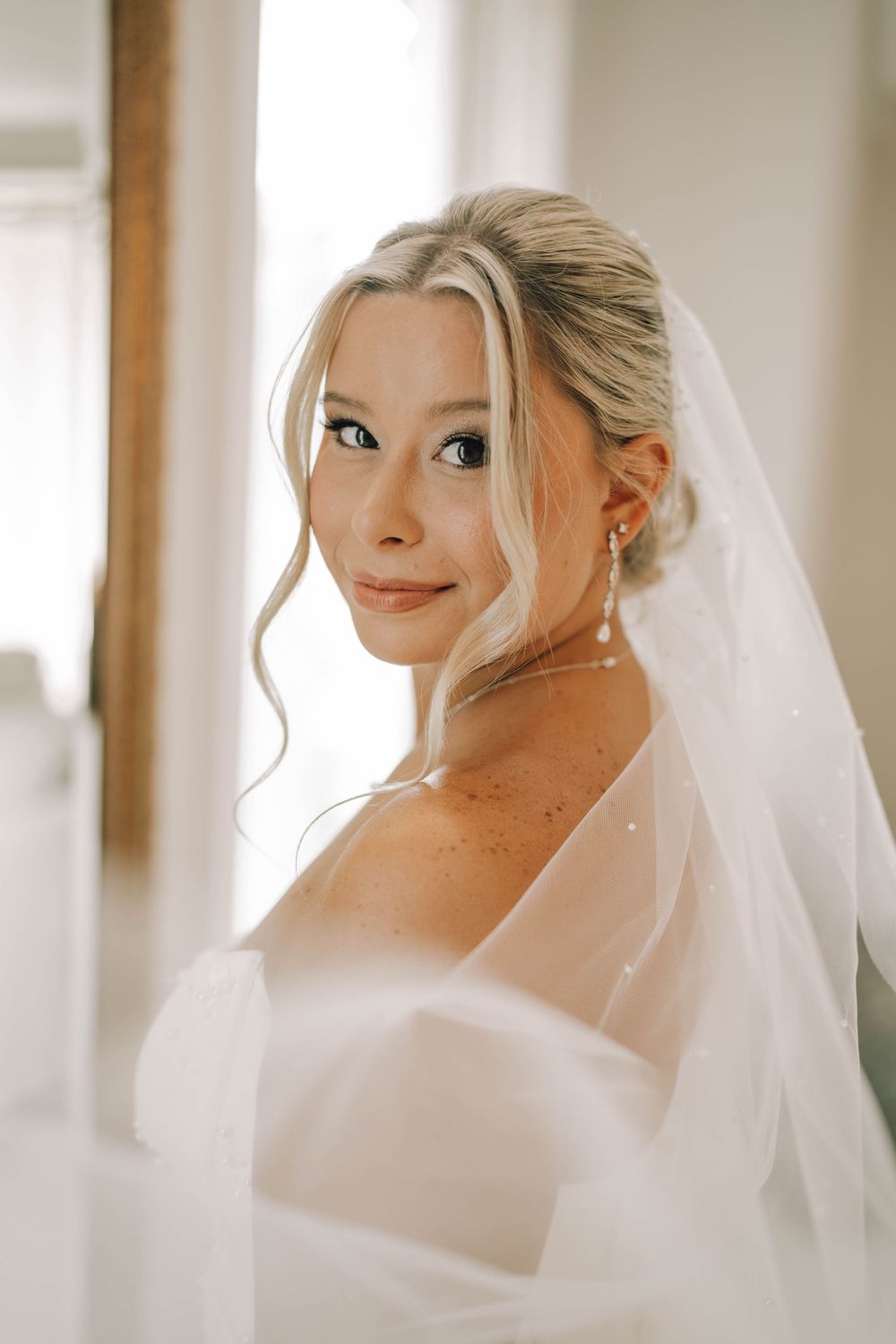 A series of five close-up bridal portraits showing playful expressions through a soft white veil.