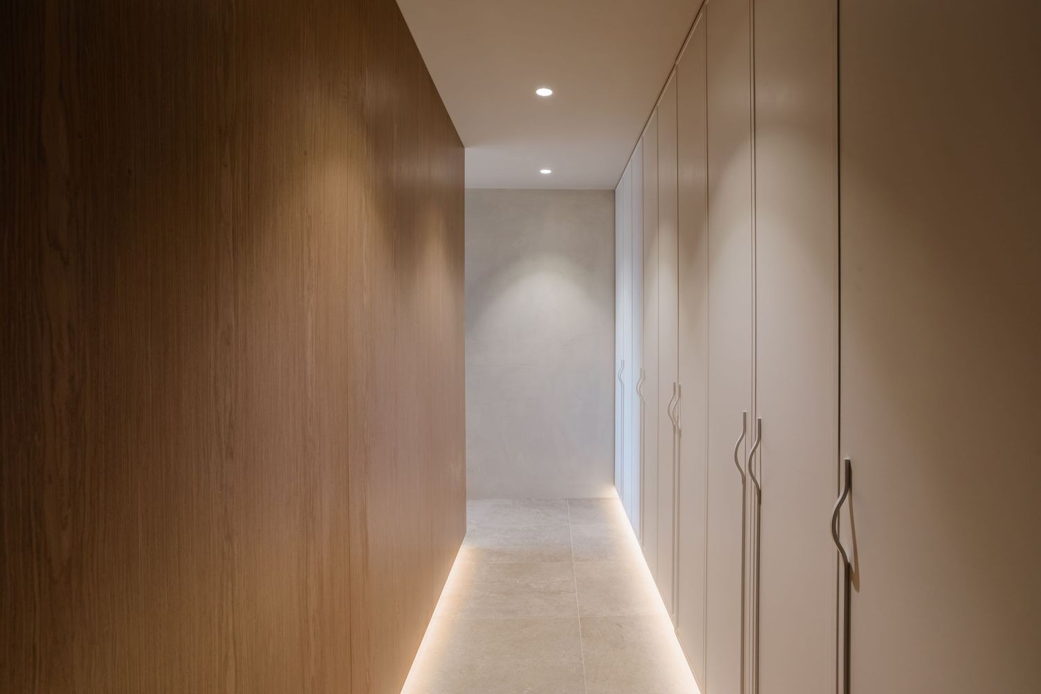 Modern hallway interior with warm wood paneling and recessed lighting creates an elegant minimalist atmosphere.
