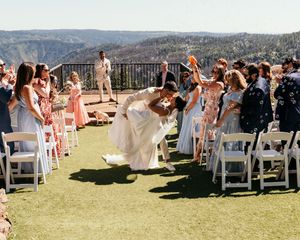 Outdoor wedding ceremony setup with white chairs on grass overlooking mountain landscape.