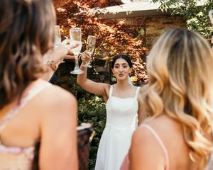 Wedding party members standing together outdoors with autumn foliage in background.