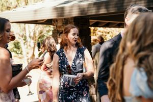 Wedding guests enjoying an outdoor celebration under natural lighting and trees.