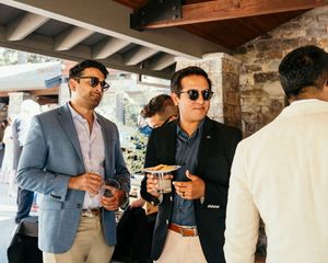 Wedding guests chatting and enjoying drinks at a rustic stone venue.