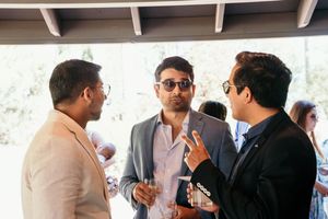 Wedding reception guests mingling and socializing at an outdoor covered venue.