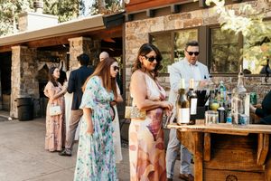 Guests gathering around an outdoor bar area at a rustic wedding venue.