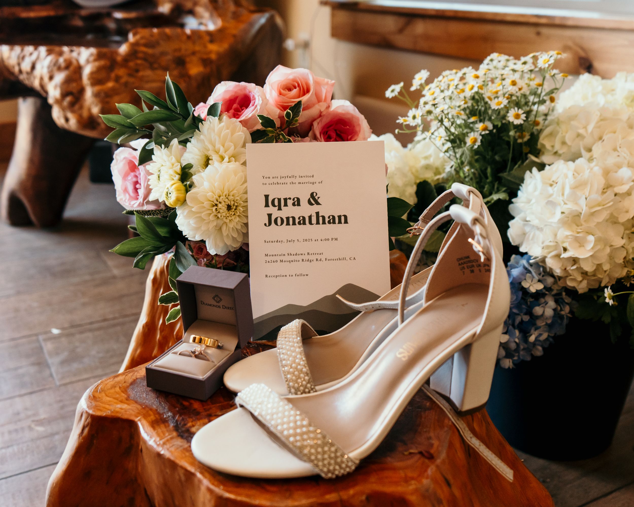Wedding details including white shoes, floral arrangements, and name cards displayed on wooden surface.