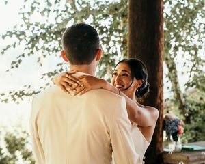 Romantic outdoor wedding moment captured under sunlit trees with soft natural lighting.