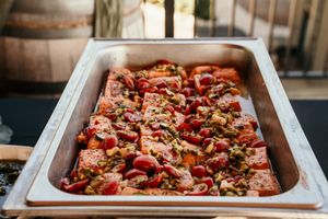 Large catering trays filled with colorful meat dishes displayed at a buffet service.