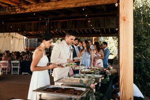Wedding reception dining area under wooden beams with guests enjoying meal.