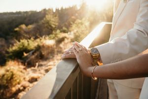 Close-up details of wedding attire and hands in golden sunlight.