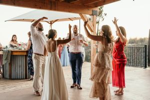 Wedding guests dance together on an outdoor patio during sunset celebrations.