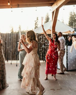 People dancing and celebrating under wooden beams at a rustic venue with natural lighting.
