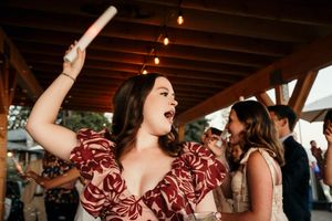 Wedding guests dancing and celebrating at an indoor reception venue with warm lighting.
