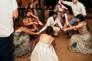 Wedding guests dance and celebrate together on a dimly lit dance floor.