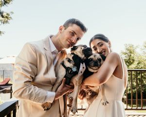 Wedding portraits featuring a couple and their pug dog against a bright outdoor backdrop.