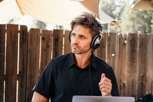 A DJ wearing headphones performs at an outdoor event behind professional equipment.