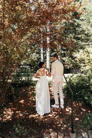Couple walks hand in hand through a garden path with autumn trees creating a romantic atmosphere.