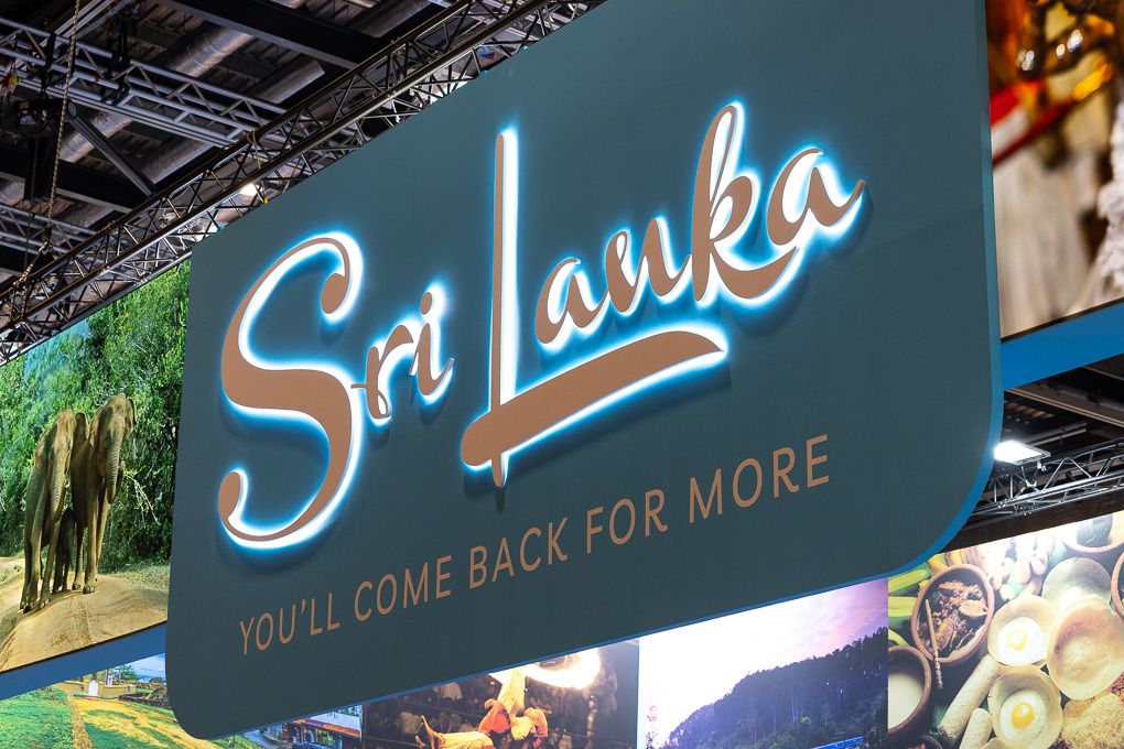 Illuminated blue neon sign for Sri Lanka tourism with tagline 'You'll come back for more' against dark background. Located at the WTM, ExCel