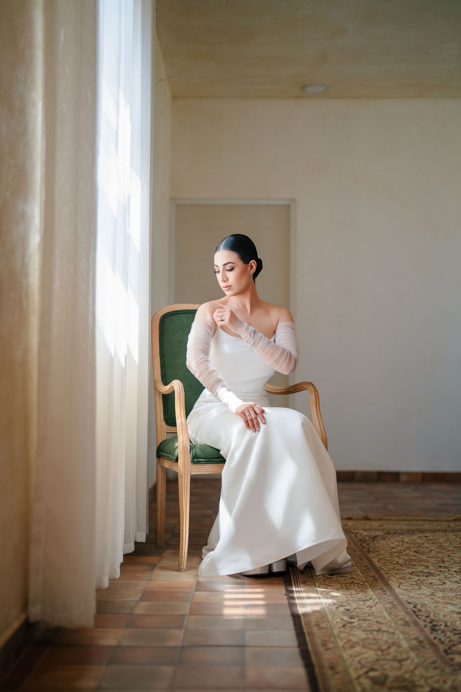 Elegant bridal portrait session in a sunlit room with vintage furniture and ornate carpet.