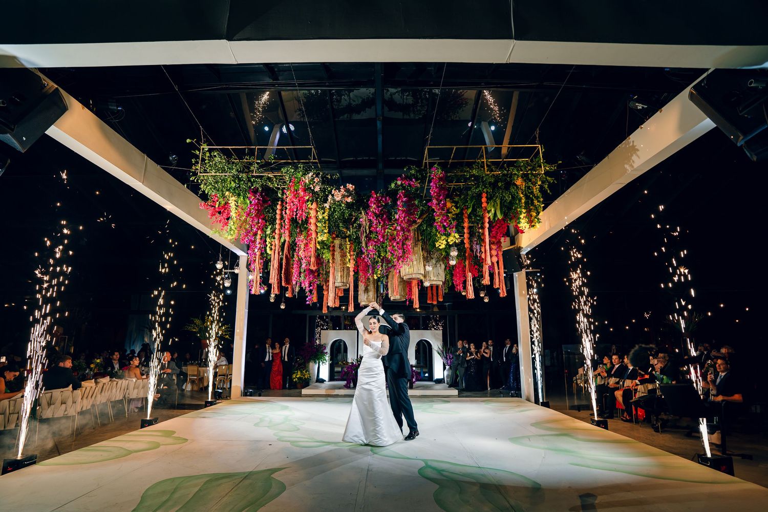 Wedding ceremony venue decorated with hanging floral arrangements and dramatic lighting.