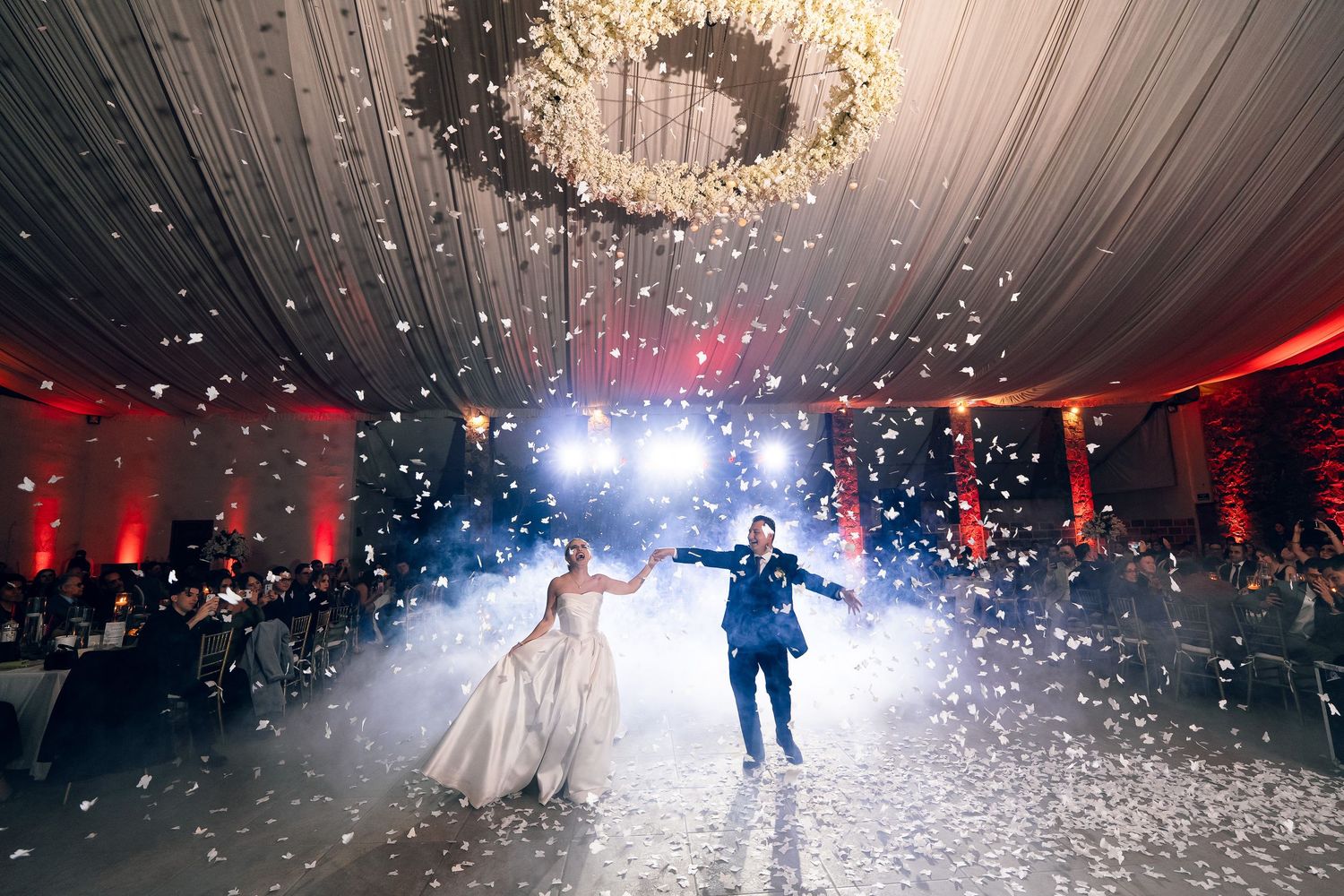 Magical first dance at wedding reception with falling snow effect and dramatic lighting.